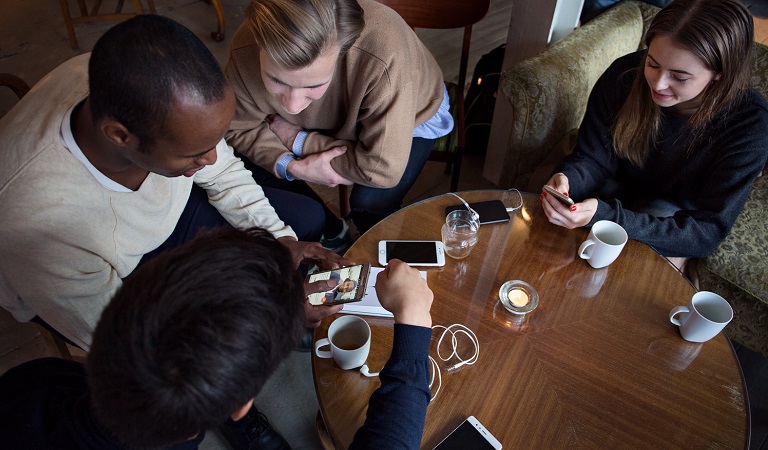 Ungdommer samlet rundt bord med mobiler